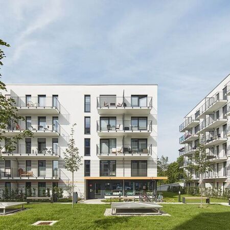 Referenz - Weiße Mehrfamilienhäuser mit Balkonen und einer zentralen Grünfläche