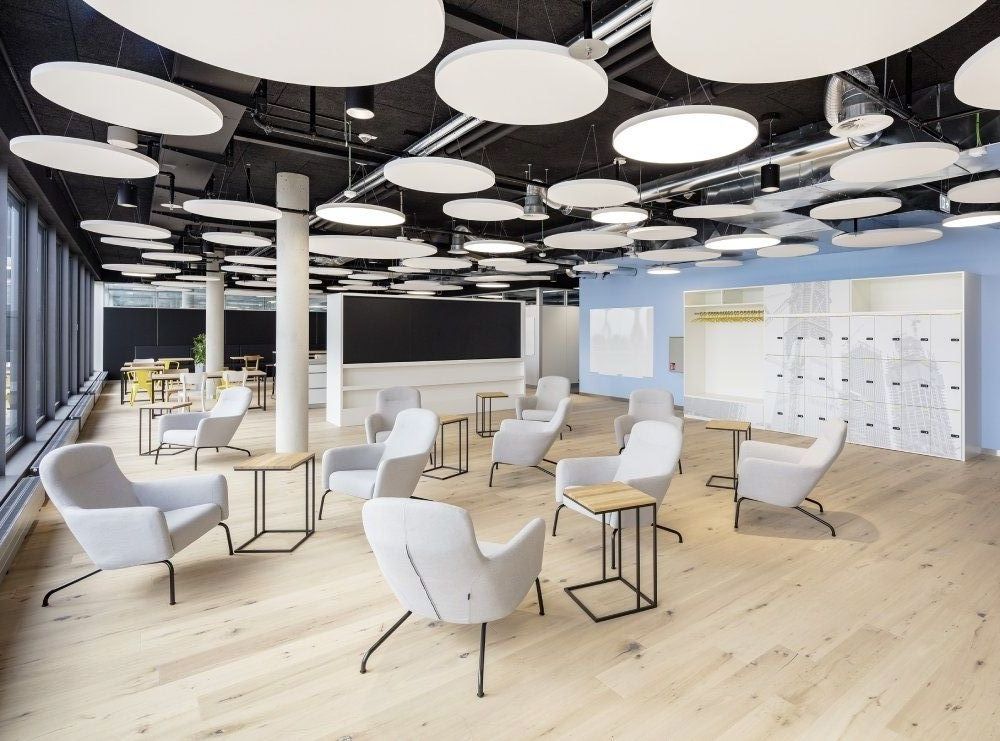 Heller Büro Lounge Bereich mit Akustikdeckenelementen und modernen Sitzmöbeln