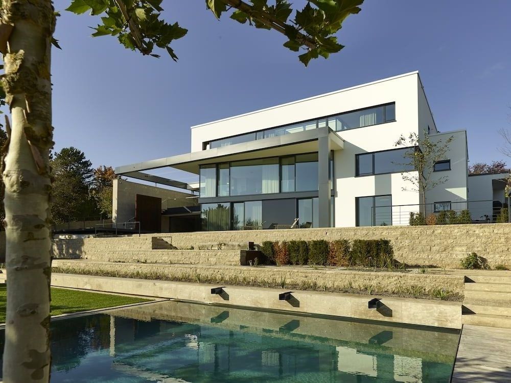 Modernes Architektur Wohnhaus mit großer Glasfassade und Pool in terrassiertem Garten